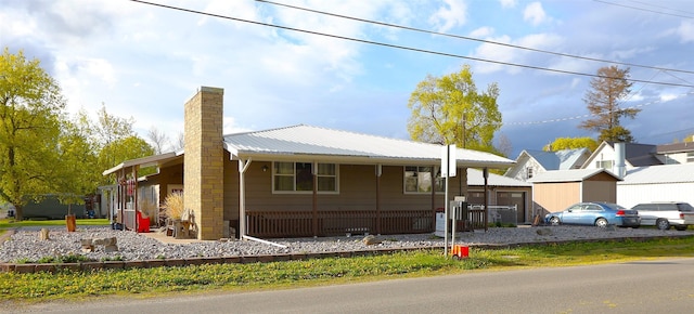 ranch-style house featuring a chimney and metal roof