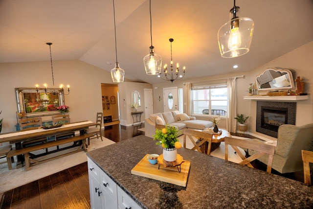 kitchen with hanging light fixtures, vaulted ceiling, white cabinets, and open floor plan