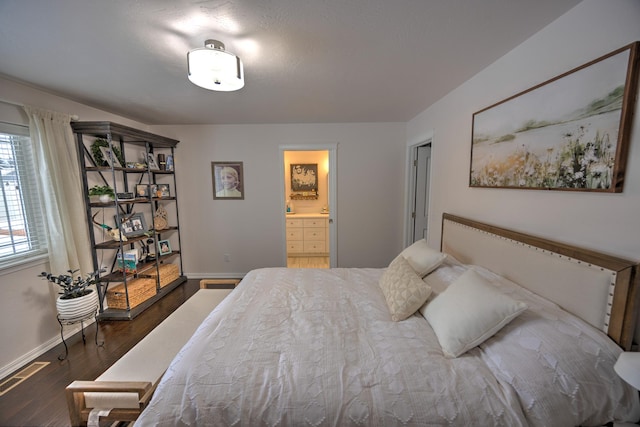 bedroom featuring visible vents, baseboards, dark wood-type flooring, and ensuite bathroom