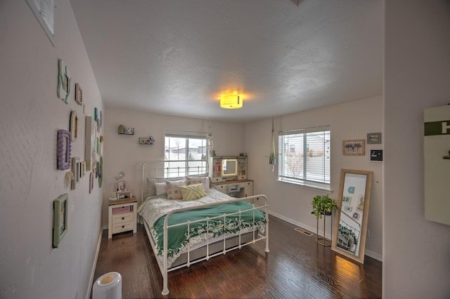 bedroom with baseboards, a textured ceiling, visible vents, and dark wood-type flooring