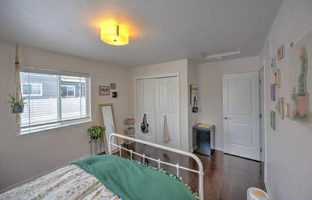 bedroom with dark wood-style floors, a closet, attic access, and baseboards