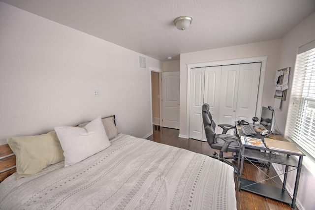 bedroom with a closet, dark wood-style flooring, visible vents, and baseboards