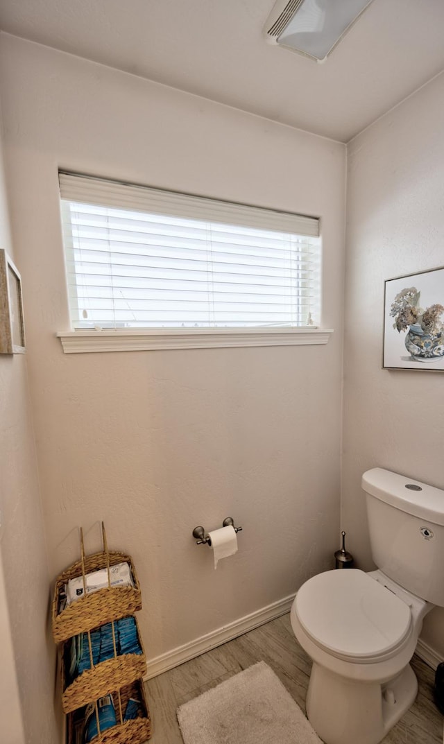 bathroom with toilet, baseboards, and wood finished floors