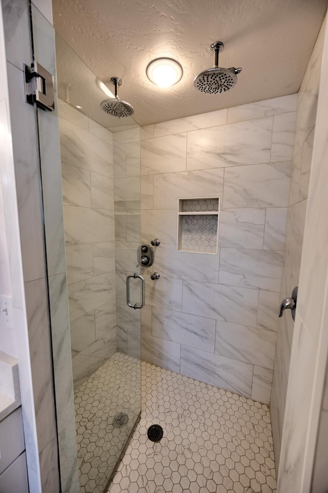 full bath with a shower stall and a textured ceiling