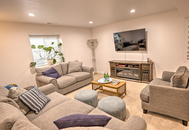 living area featuring recessed lighting, light colored carpet, a glass covered fireplace, and visible vents