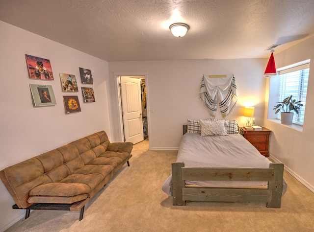 bedroom with baseboards, a textured ceiling, and light colored carpet