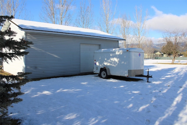 view of snowy exterior with a garage and an outdoor structure