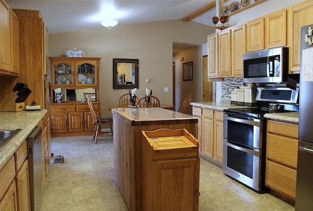 kitchen featuring backsplash, vaulted ceiling with beams, appliances with stainless steel finishes, a kitchen island, and butcher block counters