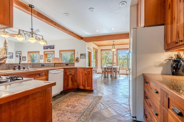 kitchen with sink, hanging light fixtures, beamed ceiling, kitchen peninsula, and white appliances