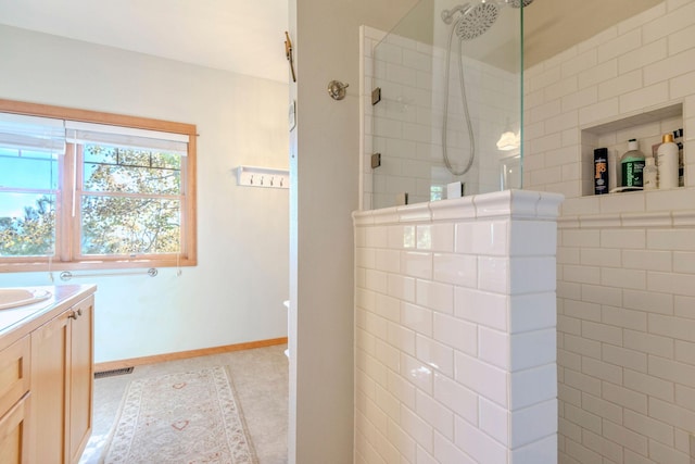 bathroom featuring tile patterned flooring, a tile shower, and vanity