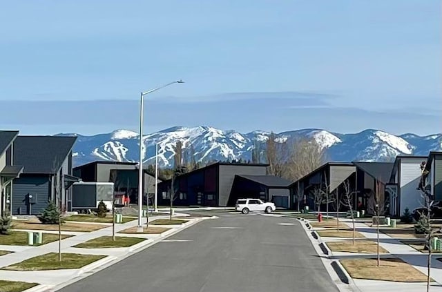 3416 Goldenrod Ln, Kalispell, MT 59901 - view of asphalt street featuring a mountain view, street lights, sidewalks, and curbs
