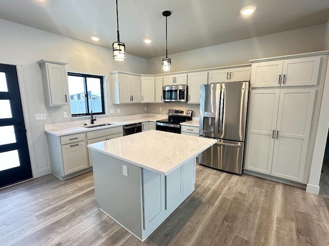 kitchen featuring a center island, white cabinets, sink, decorative light fixtures, and stainless steel appliances