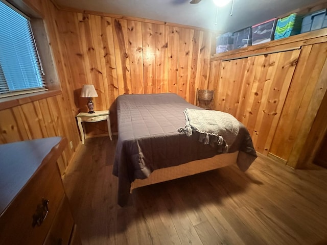 bedroom featuring hardwood / wood-style floors, ceiling fan, and wood walls