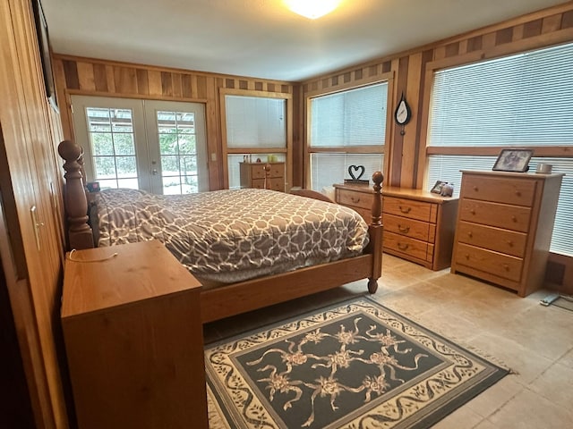 bedroom with wooden walls, access to outside, and french doors