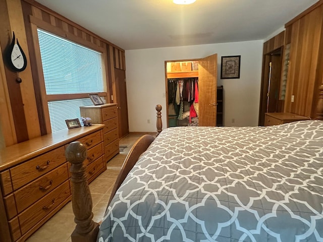 tiled bedroom featuring a walk in closet and a closet