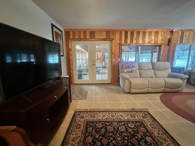 living room with wooden walls, french doors, and light tile patterned floors