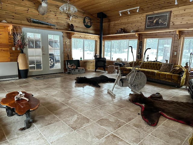 living room with wood walls, a wood stove, french doors, rail lighting, and wood ceiling