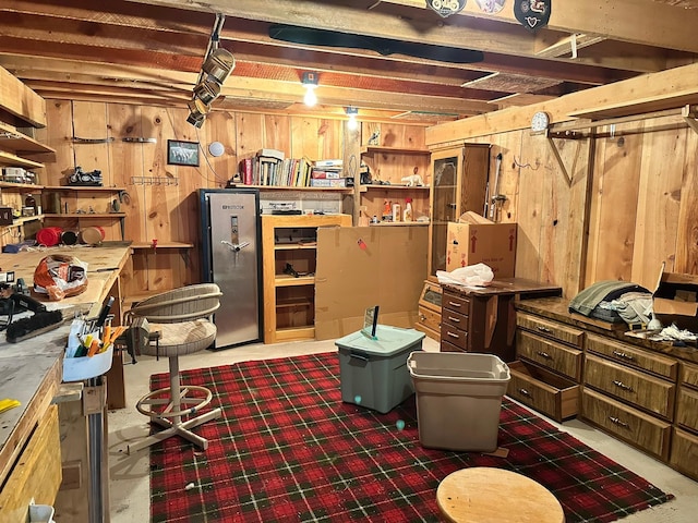 basement with wood walls and stainless steel refrigerator