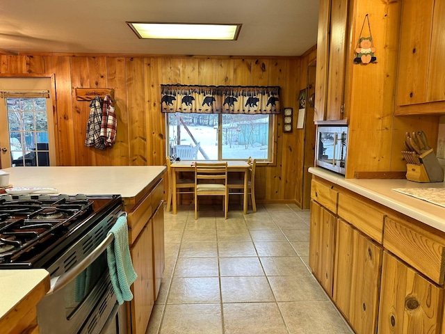 kitchen featuring light tile patterned floors, range, and wood walls