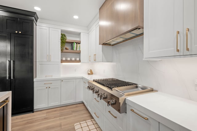 kitchen with white cabinetry, built in fridge, custom range hood, and stainless steel gas stovetop