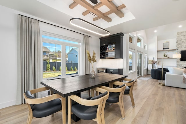 dining room with beam ceiling, plenty of natural light, coffered ceiling, and light wood-type flooring