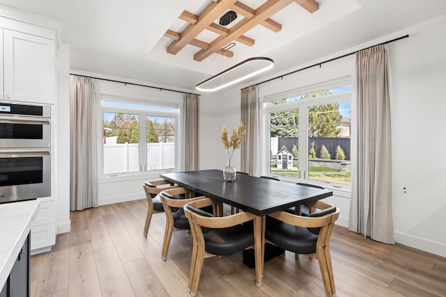 dining space featuring light wood-type flooring, a wealth of natural light, and coffered ceiling