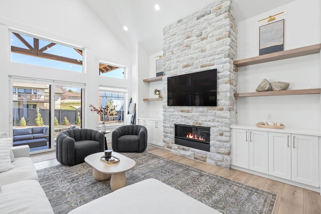 living room featuring a fireplace, light hardwood / wood-style flooring, and high vaulted ceiling