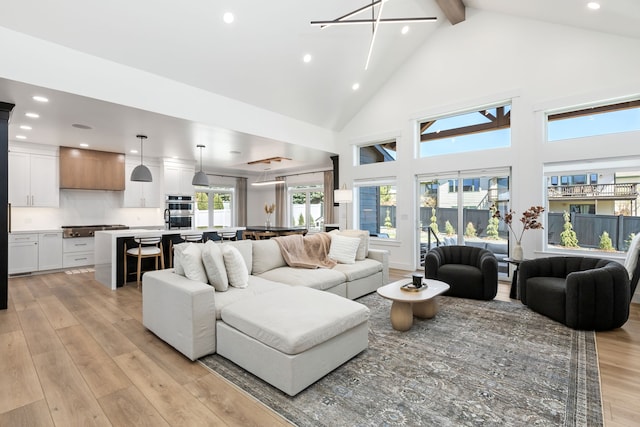 living room with a chandelier, beam ceiling, high vaulted ceiling, and light hardwood / wood-style flooring