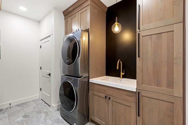 laundry room with cabinets, stacked washing maching and dryer, and sink