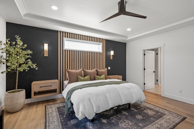 bedroom with ceiling fan, light wood-type flooring, crown molding, and a tray ceiling