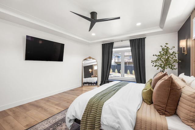 bedroom featuring a tray ceiling, ceiling fan, light hardwood / wood-style floors, and ornamental molding