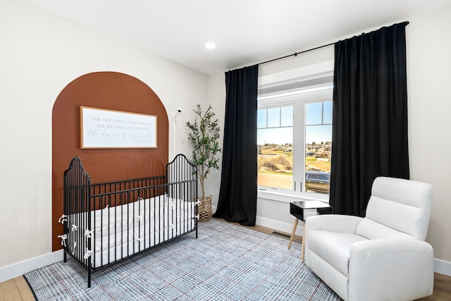 bedroom with hardwood / wood-style flooring and a crib