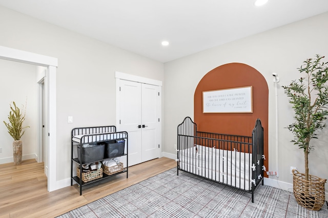 bedroom with a nursery area and wood-type flooring