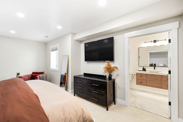 carpeted bedroom with ensuite bath and sink