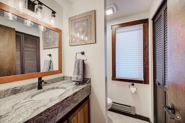 bathroom with toilet, vanity, and a baseboard heating unit