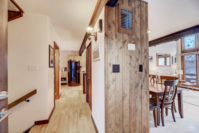 hall with light wood-type flooring and wooden walls