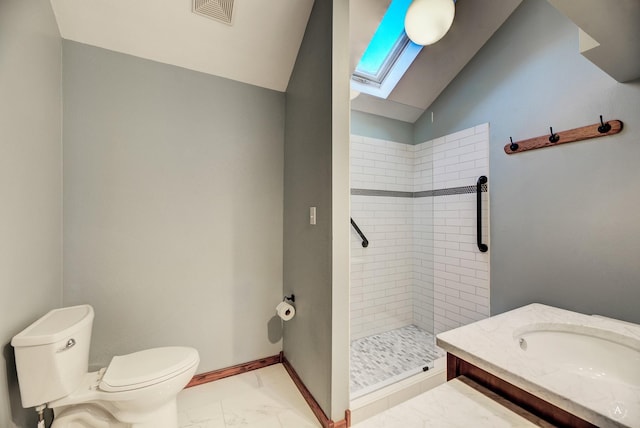 bathroom with tiled shower, lofted ceiling with skylight, vanity, and toilet