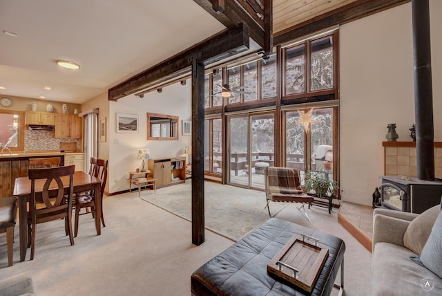 living room featuring light carpet, a high ceiling, and a wood stove