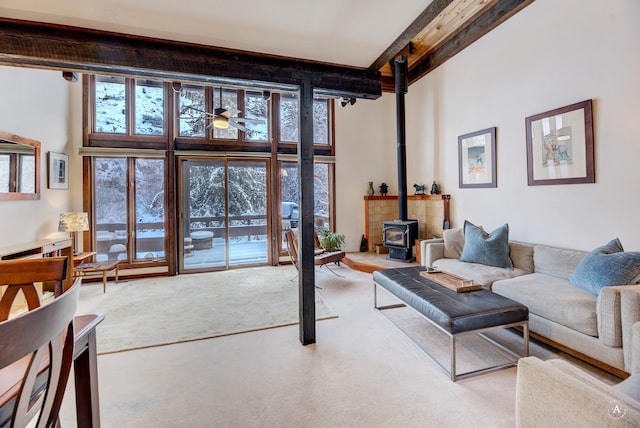 living room featuring a high ceiling, a wood stove, and a wall of windows