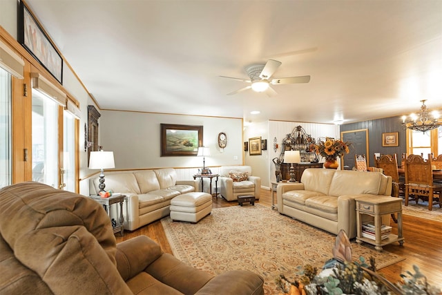 living room with ceiling fan with notable chandelier and hardwood / wood-style flooring