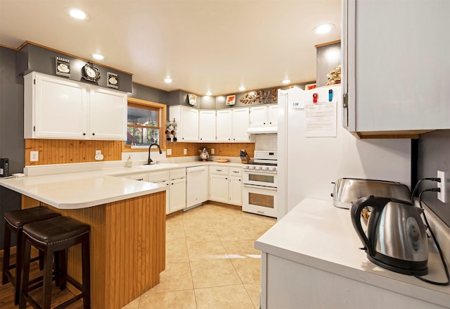 kitchen featuring kitchen peninsula, white cabinetry, sink, and white appliances