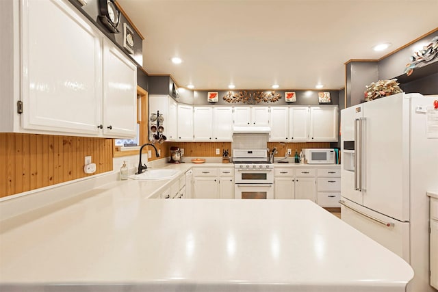 kitchen featuring white cabinetry, sink, tasteful backsplash, kitchen peninsula, and white appliances