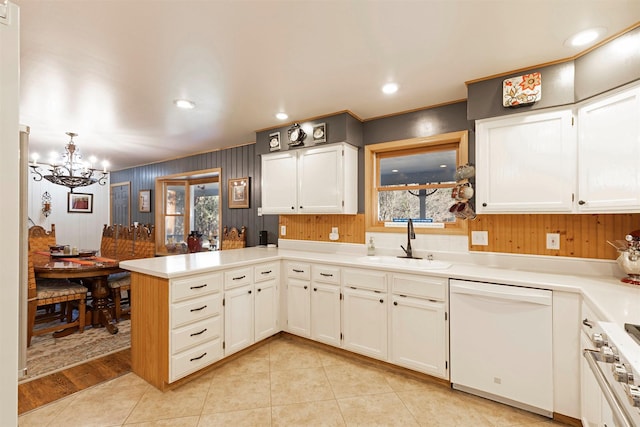 kitchen featuring kitchen peninsula, white dishwasher, sink, a chandelier, and white cabinetry