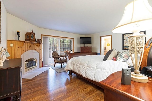 bedroom with a tile fireplace and wood-type flooring