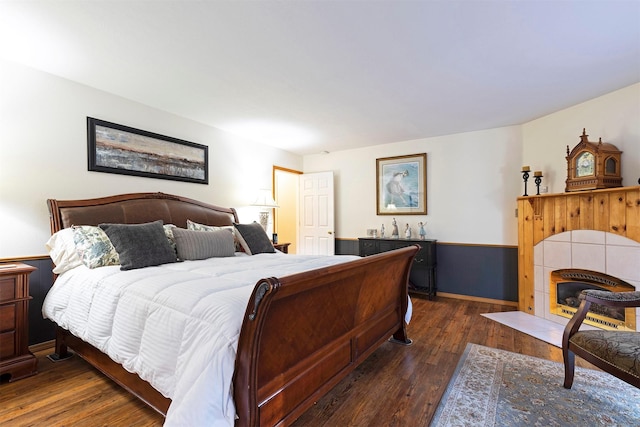 bedroom with dark hardwood / wood-style flooring and a tiled fireplace