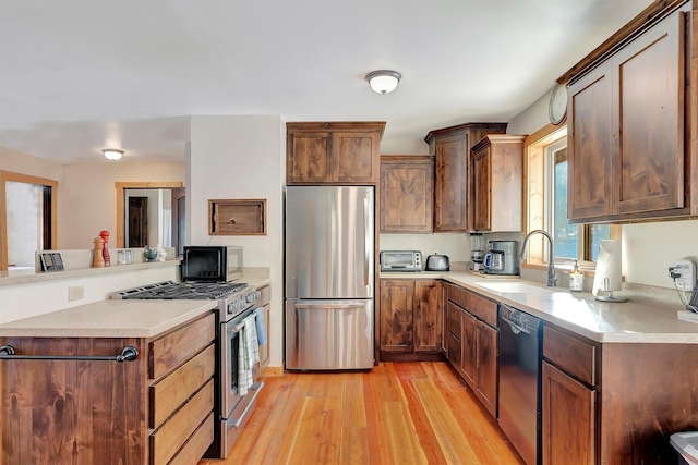 kitchen featuring sink, black appliances, and light wood-type flooring