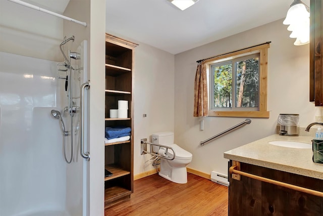 bathroom featuring walk in shower, a baseboard heating unit, hardwood / wood-style floors, toilet, and vanity