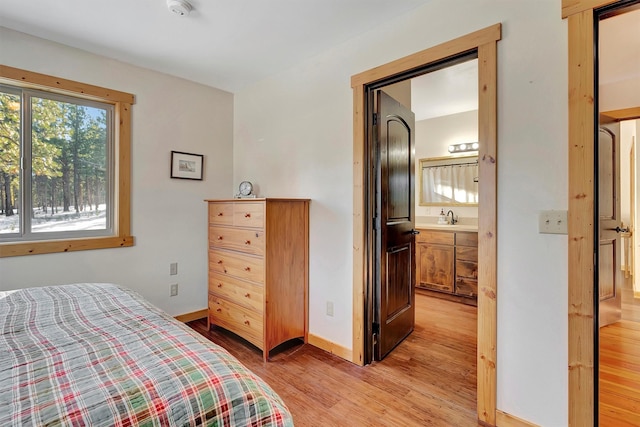 bedroom featuring ensuite bath, light hardwood / wood-style flooring, and sink