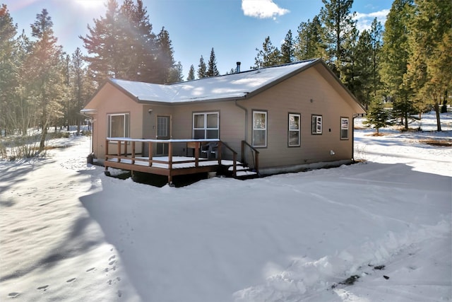 snow covered back of property featuring a deck