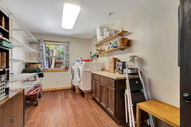 clothes washing area with cabinets, washer and clothes dryer, and light hardwood / wood-style floors